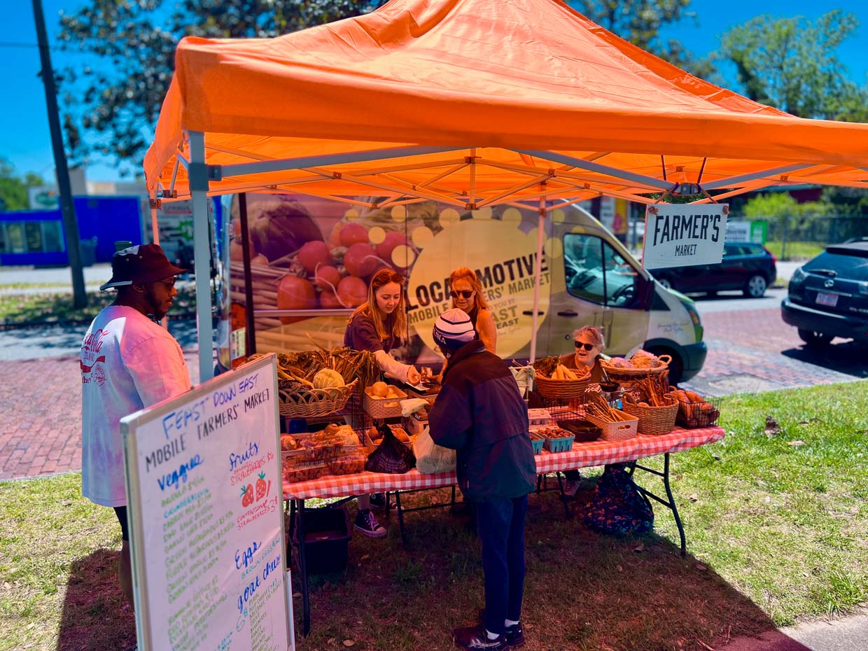 local motive market tent with guest purchasing produce